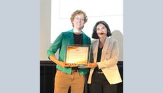 Natalie Klco on the left wearing a teal blazer and khaki pants holds a framed certificate alongside Zohreh Davoudi on the right, who wears a light striped blazer and black pants.