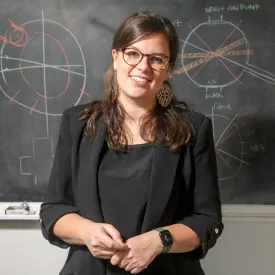 Professional headshot of a woman in front of a chalkboard. 