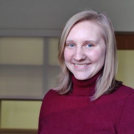 a woman smiling at the camera and wearing a red turtleneck