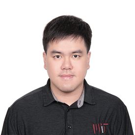 A young man wearing a black shirt stands facing the camera with a white background.